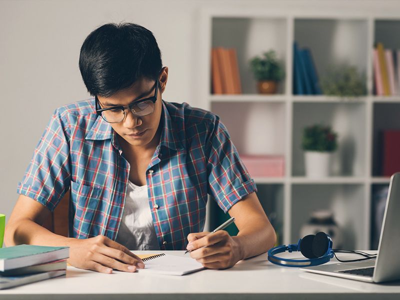 Student writing term paper at a quiet study desk