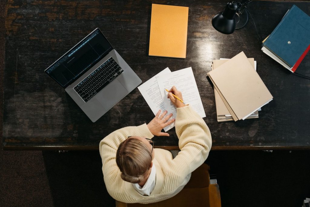 Teacher reviewing a student essay for AI writing next to a laptop — what AI checker is most similar to Turnitin
