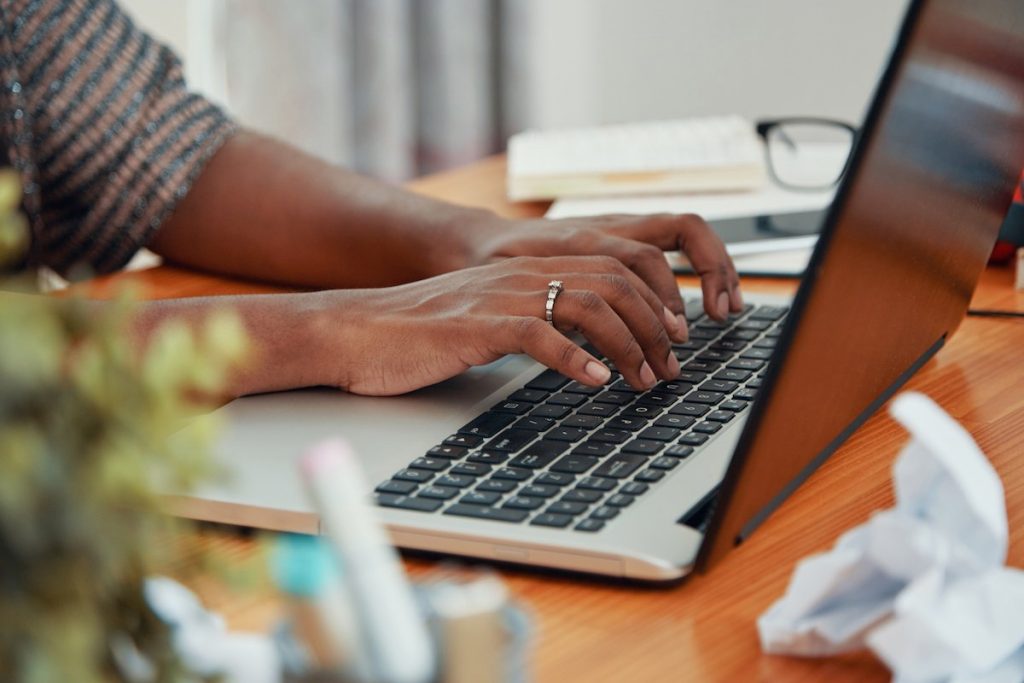 Writer typing on a laptop in a home office, AI content detection concept