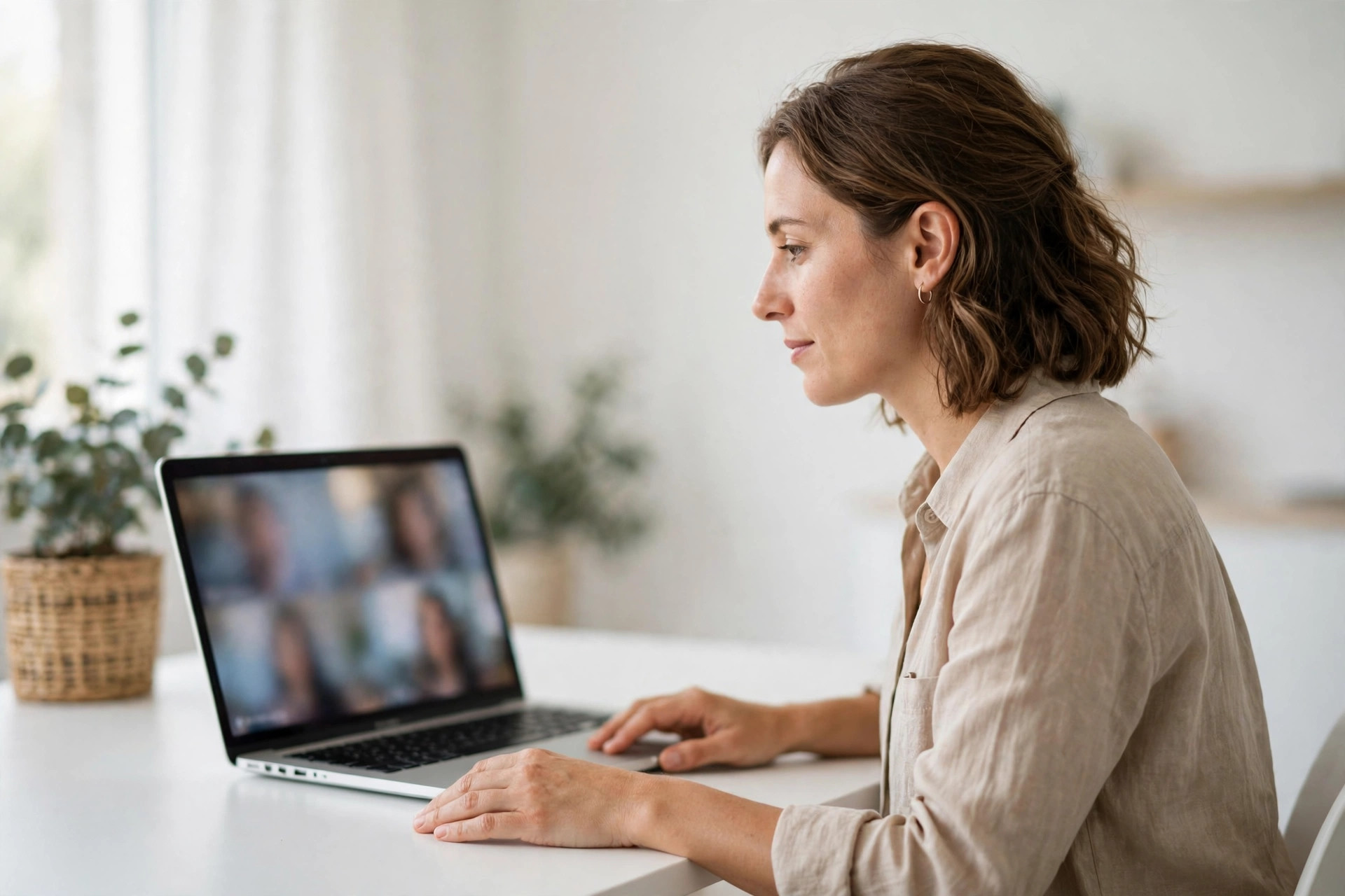 Job candidate in a video interview on a laptop at a white desk in a bright room - The Algorithm book review hiring scene