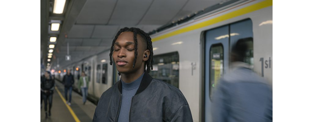 Person wearing wireless earbuds while traveling in a city